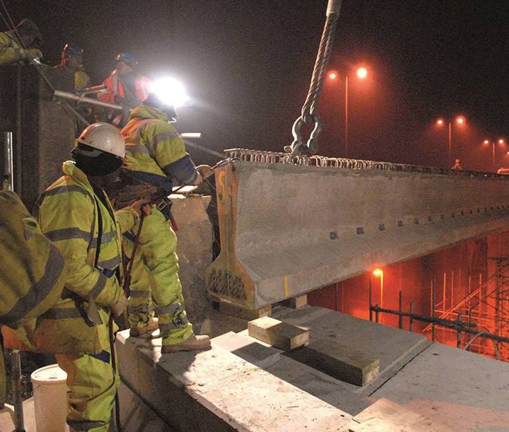 Construction workers wearing safety gear working on the M1 Widening project at night 