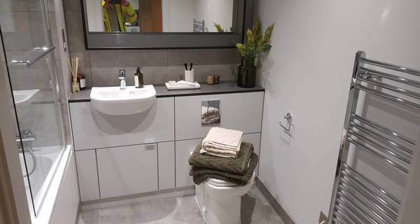 Modern bathroom in a Mustard Wharf unit,  with a large mirror and minimalist white and grey tiles.