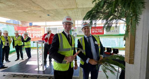 Representatives from Sir Robert McAlpine hammering a ceremonial tree branch onto the building structure