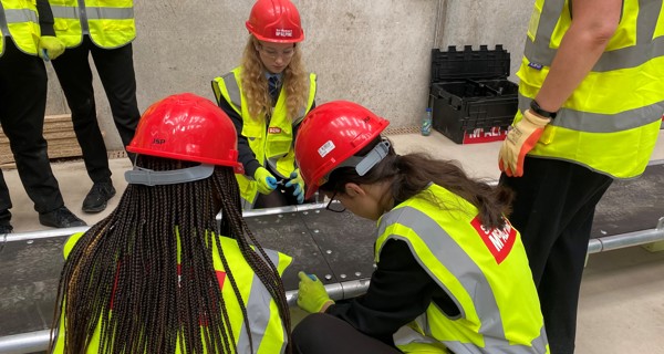 Students working together to construct a 13m cable stay bridge as part of a civil engineering skills workshop.