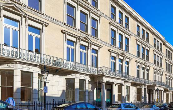 Close-up of the De Vere Gardens’ exterior, featuring a mix of modern glass elements and traditional Victorian architecture along Kensington Road.