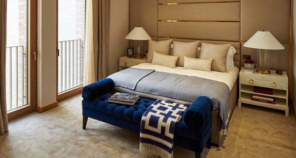 Bedroom in a De Vere Gardens apartment, featuring large windows, elegant furnishings, and soft ambient lighting.