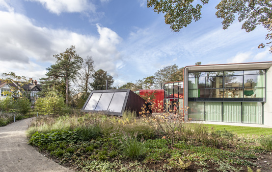 The exterior garden view of  Maggie's Royal Marsden, with lush greenery, walking paths.