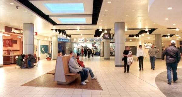  A bustling retail corridor within the Xscape complex, lined with stores and shoppers walking along.