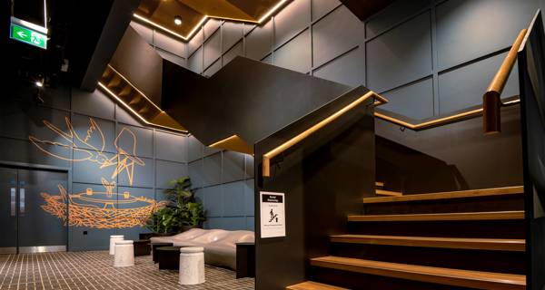 Wide view of the staircase at Mustard Wharf, featuring sleek wooden handrails and warm yellow lights.