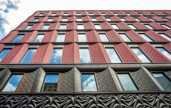 Close-up of the Ilona Rose House façade, displaying the intricate rose-patterned design on the pale pink cladding