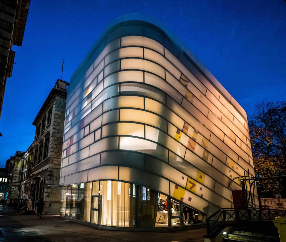 Exterior view of Maggie’s Cancer Care Centre at St Bartholomew’s Hospital, featuring its distinctive ‘lantern-like’ design with curving glass and concrete elements