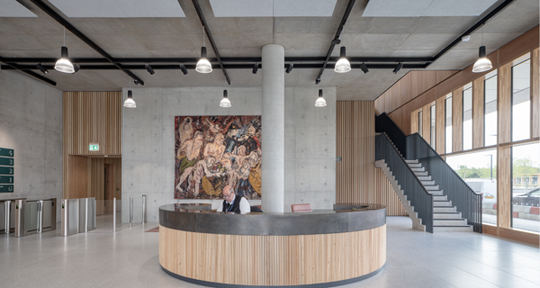 Main reception area of 1 New Park Square featuring exposed concrete walls and art installations illuminated by modern lighting.